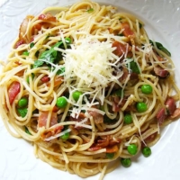 bowl of spaghetti with bacon, peas and chilies