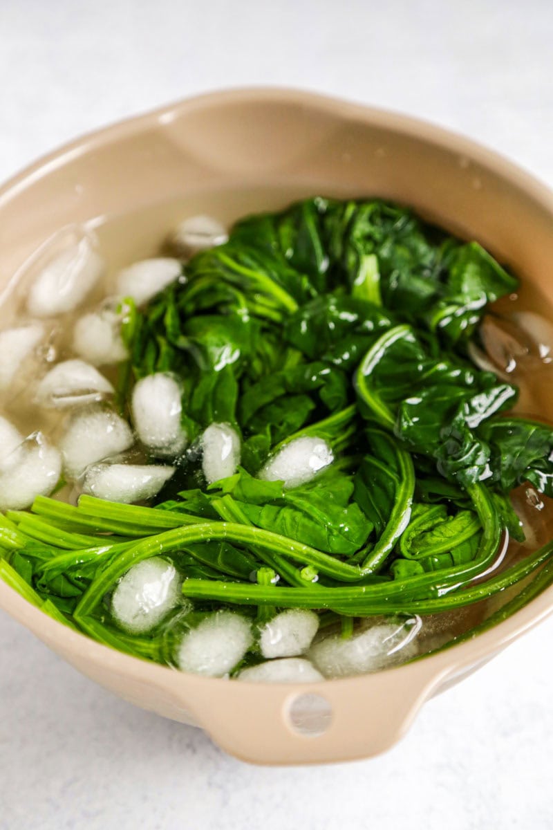 Blanched spinach cooling in a bowl of ice water