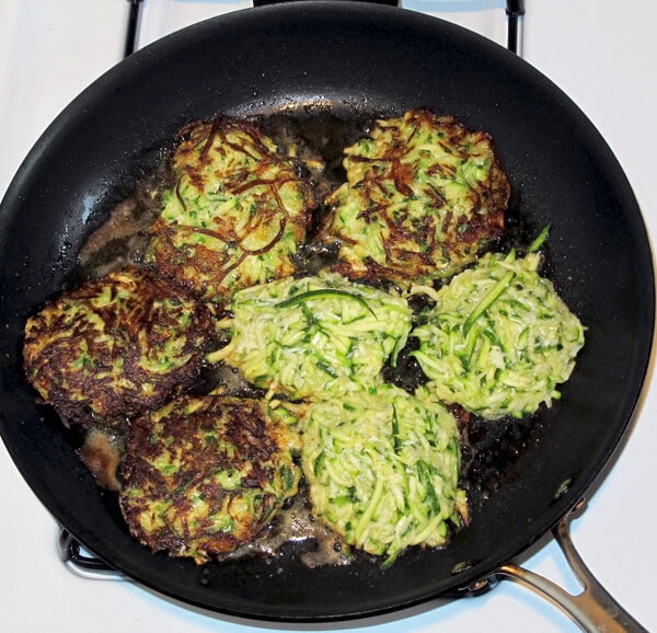 zucchini cakes frying in a pan