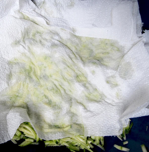 grated zucchini in bowl with paper towel