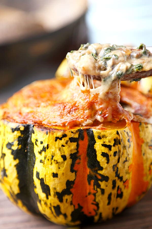 Cheesy Baked Acorn Squash - A delicious fall recipe your entirely family will love (and it looks so pretty!). Roasted acorn squash stuffed with cheese, baby kale and a creamy mushroom sauce. This is an easy dinner recipe, comfort food for the fall and winter. #fallrecipes #acornsquash #homemade #yummy | pickledplum.com
