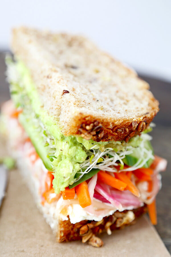 California Veggie Sandwich - There is nothing boring about this veggie sandwich! Work your way through layers and layers of bold flavors in this California veggie sandwich with pickled carrots, mashed avocado, lemony goat cheese spread, cucumbers, sprouts and baby spinach. Recipe, sandwich, snack, healthy, vegetables | pickledplum.com