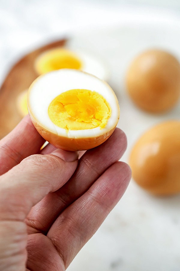 Close up of a hand holding a sliced ramen egg.