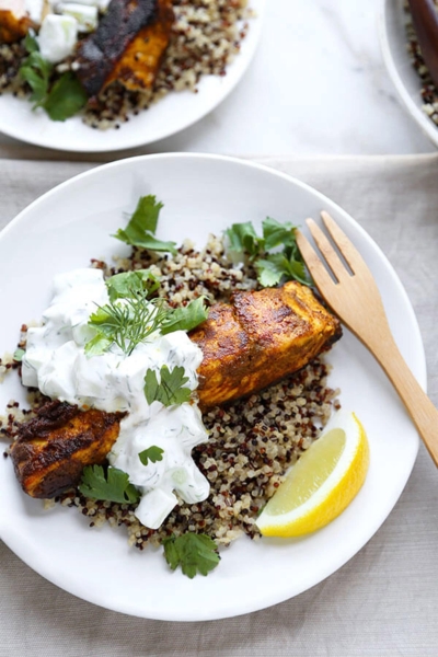 salmon tikka on a bed of quinoa topped with cucumber raita