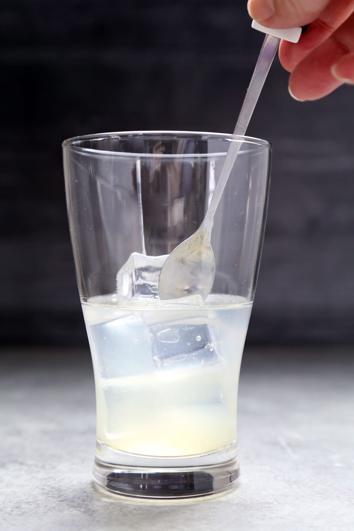 Glass with ice cubes, lemon juice, and soju