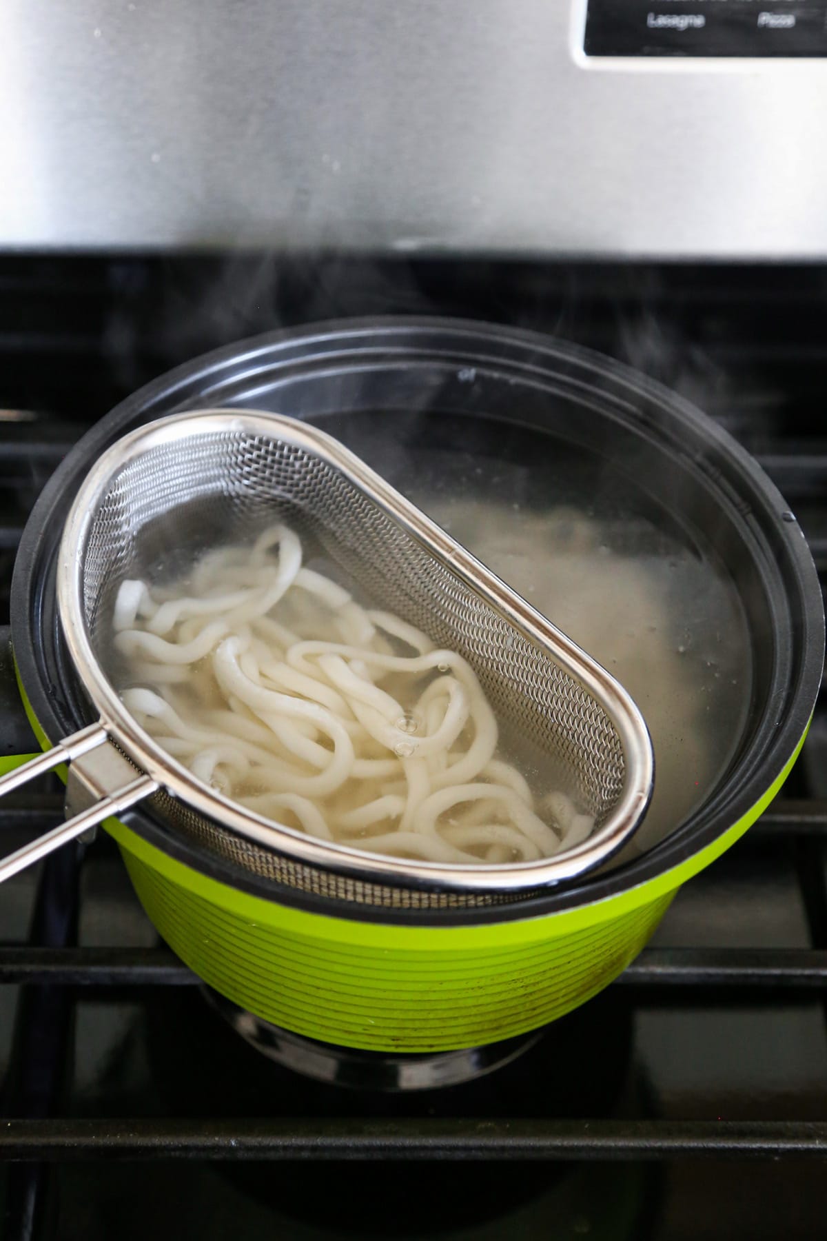 a pot of boiling water with udon noodles inside